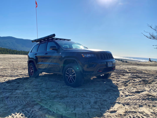 Jeep on the top of a dune overlooking the beach and beautiful coastline.