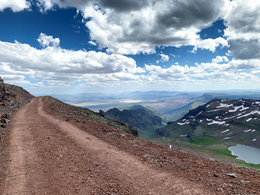 Cliffside trail to the summit of a mountain, with snow capped gorges on the side.